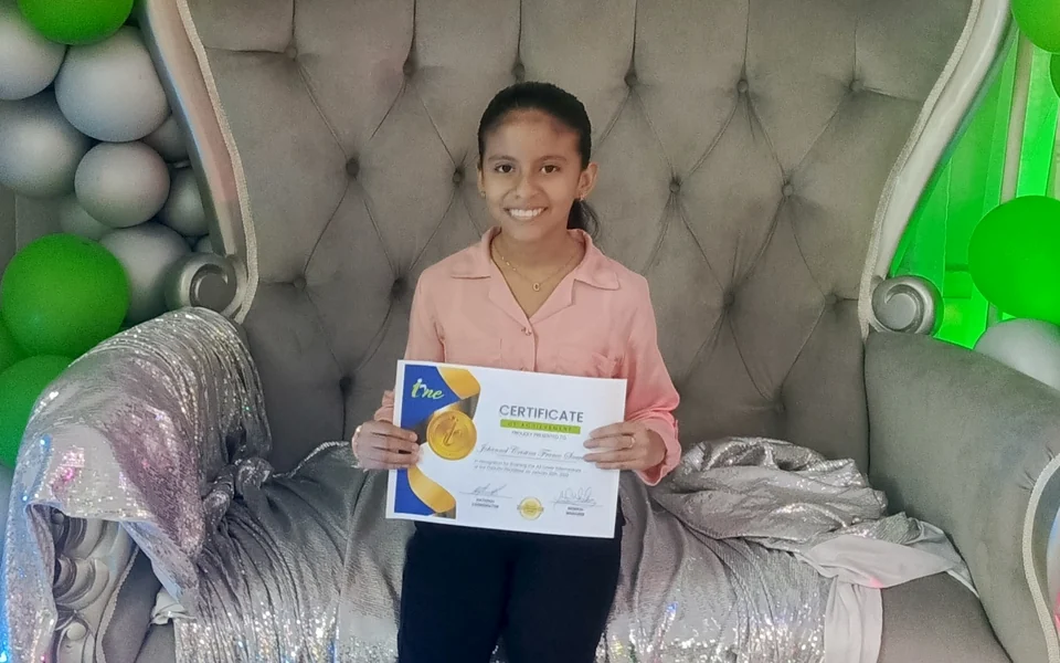 Niña graduada de I-ONE con su certificado